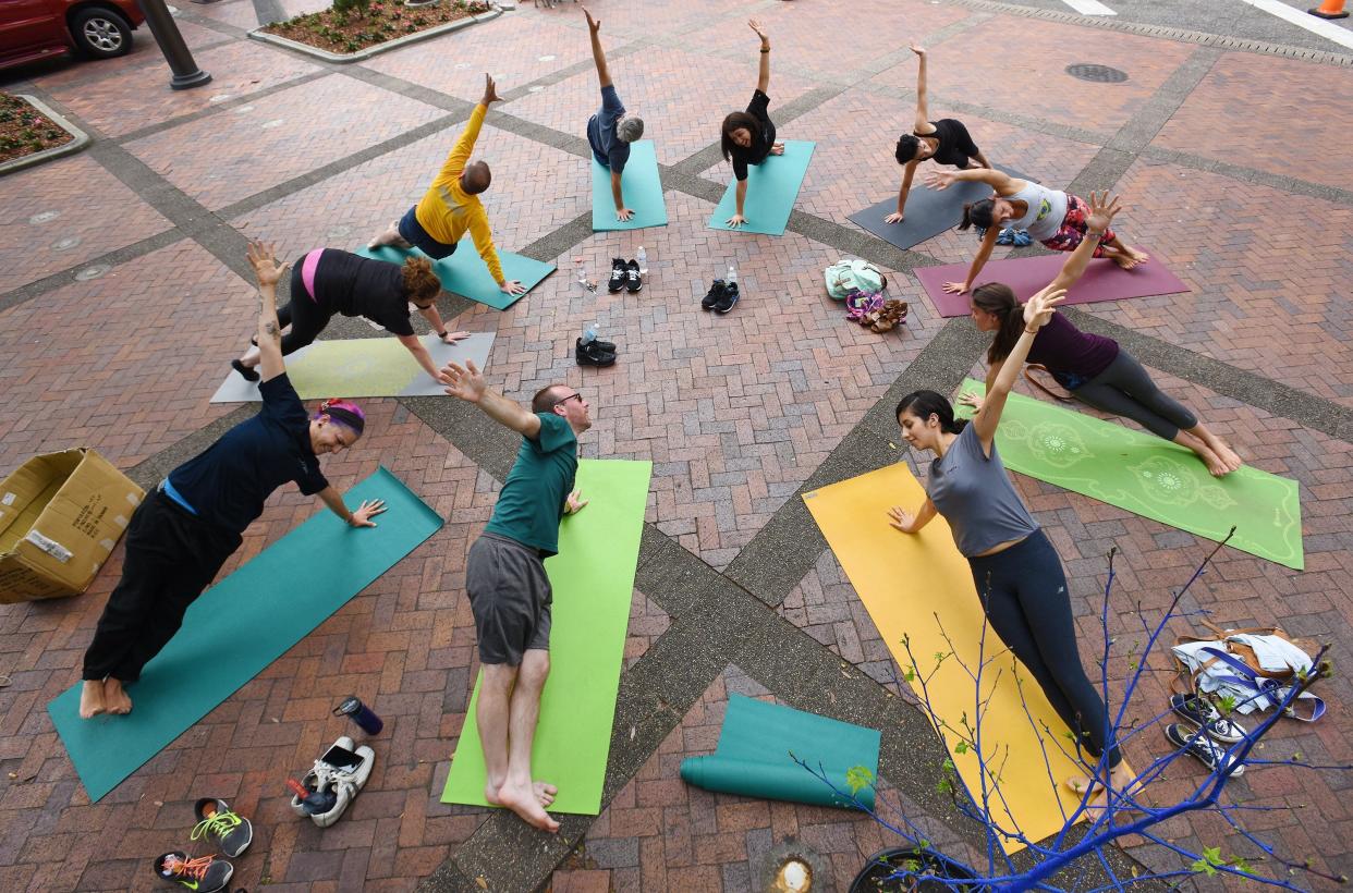 In 2016, participants stretch as part of a free yoga class in the former Hemming Park (now James Weldon Johnson Park) held by Yoga 4 Change. Self-care and community support are both ways Jacksonville residents can combat stress.