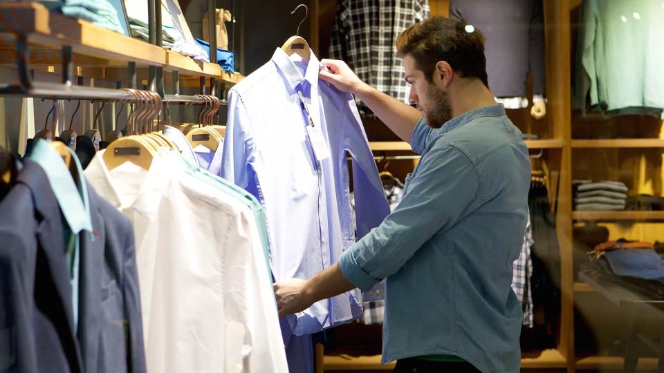 Portrait of a young man shopping for clothes at store.