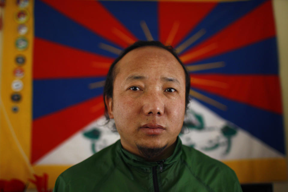 In this Wednesday, April 2, 2014 photo, Sonam Tashi sits in front of a Tibetan flag at the Tibetan refugee camp in Katmandu, Nepal. Tashi said he and another Tibetan Sonam Chodon were held for weeks after being picked up by police who broke up a small rally in front of the Chinese Embassy visa office on March 10 and were released only this week without charges or access to legal aid in a sign that authorities are bowing to pressure from China. The government on Thursday denied accusations in a report by Human Rights Watch that it is mistreating Tibetans. Nearly 20,000 Tibetans who fled their homeland now live in Nepal. (AP Photo/Niranjan Shrestha)