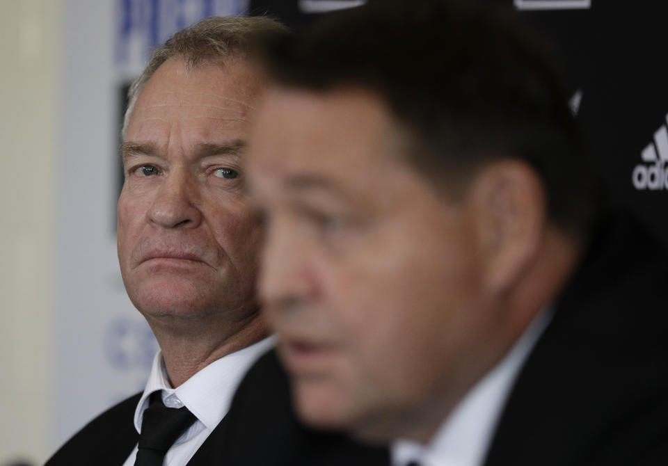 New Zealand All Blacks selector Grant Fox, left, watches as coach Steve Hansen answer's questions during a press conference at the Prebbleton Rugby Club on the outskirts of Christchurch, New Zealand, Monday, Oct. 15, 2018. The All Blacks have taken the unprecedented step of naming a player based in Japan among an enlarged 51-man squad for autumn test matches against Australia, Japan, England, Ireland and Italy. (AP Photo/Mark Baker)