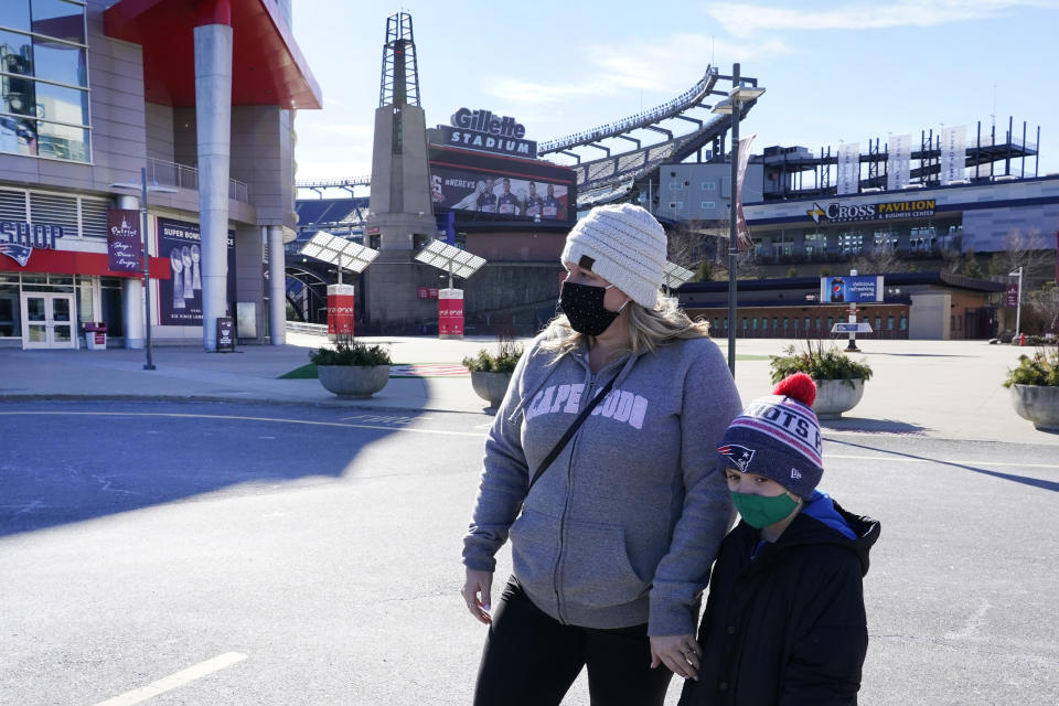 Kelly Roccabello and her son, Giovanni, 6, walk outside the pro shop at Gillette Stadium, Monday Jan. 25, 2021, in Foxborough, Mass. Tom Brady is going to the Super Bowl for the 10th time, and New England Patriots football fans are cheering for him -- just like before. (AP Photo/Elise Amendola)