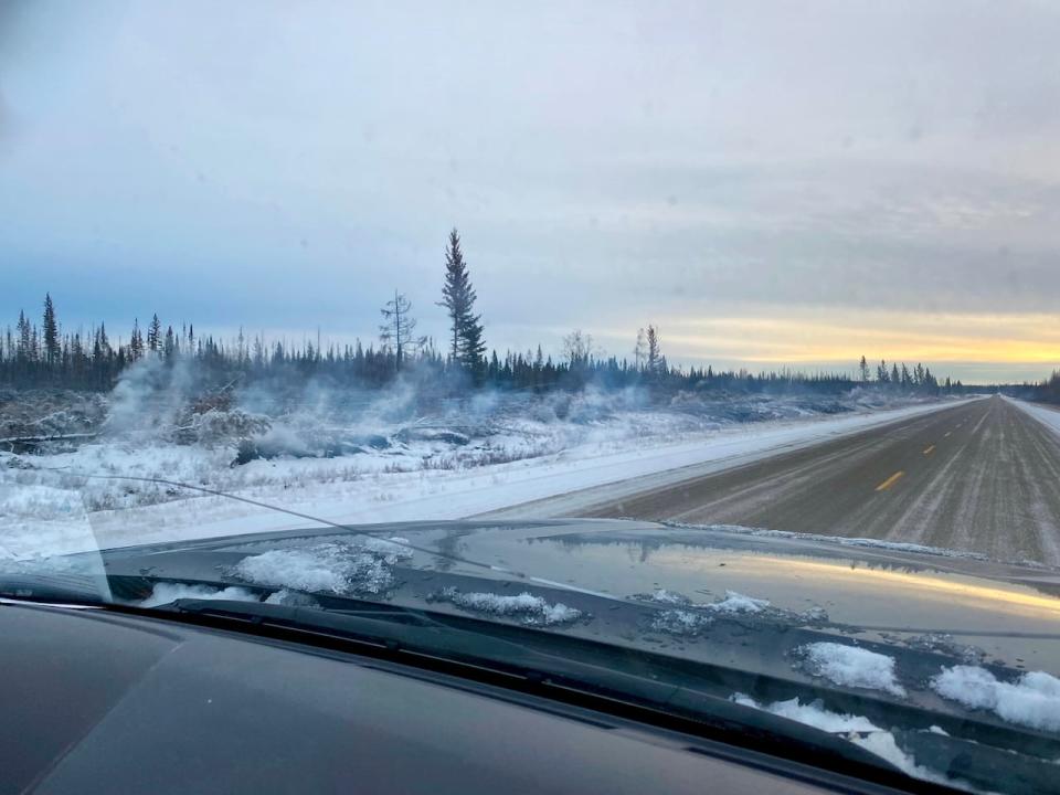 Smoke drifts upward from snow along the side of Highway 1 near Enterprise, N.W.T., in early December 2023. (April Hudson/CBC - image credit)
