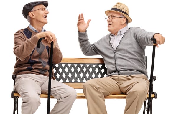 Two old men with canes, sitting on a bench talking and laughing