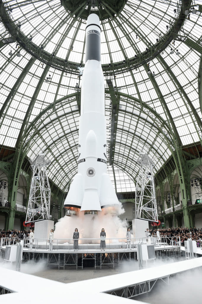 A rocket behind models standing in a row