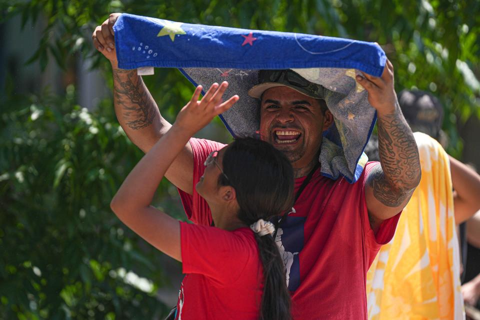 Michael Rodriguez uses a towel to provide shade for his daughter Leah Rodriguez while waiting in line at Barton Springs Pool on Monday.