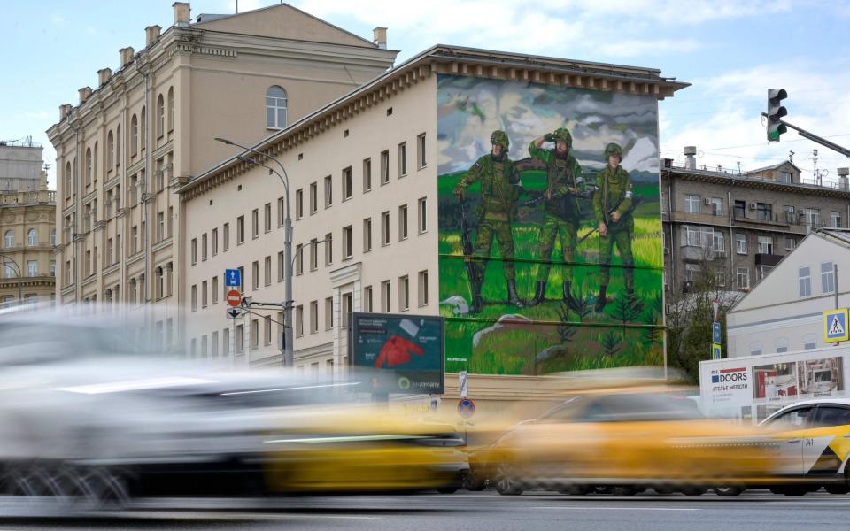 A mural depicting three armed Russian servicemen standing in a field, with Z symbols spotted on uniforms, adorns a building in Moscow - NATALIA KOLESNIKOVA/AFP