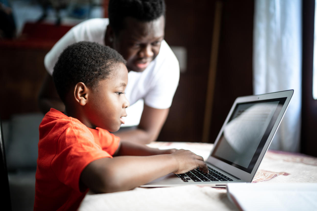 Father and son studying with laptop on an online class at home