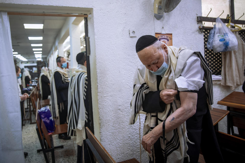 Holocaust survivor Yehoshua Datsinger places tefillin on his arm above the Auschwitz concentration camp identification number tattoo, during morning prayer at a synagogue limited to 20 people during lockdown, in Bnei Brak, Israel, Monday, Sept. 21, 2020. Photographer Oded Balilty said he was struck that even though older people were the most vulnerable to the coronavirus, Datsinger still went to synagogue every morning to pray. “He survived this latest war as well,” Balilty said. (AP Photo/Oded Balilty)