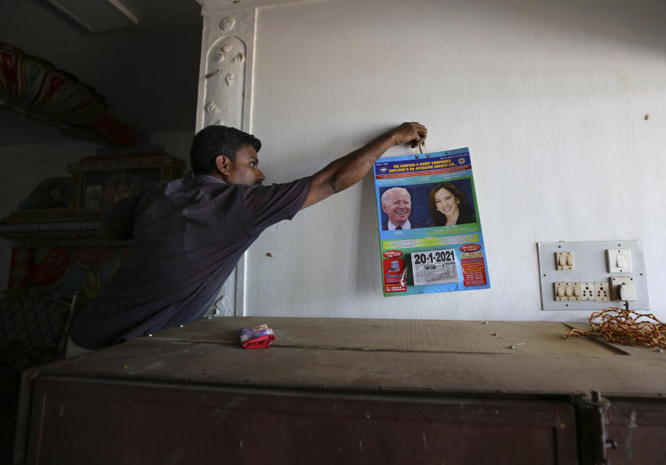 A villager hangs a calendar featuring photographs of U.S. President-elect Joe Biden and Vice President-elect Kamala Harris inside a wedding hall in Thulasendrapuram, the hometown of Harris' maternal grandfather, south of Chennai, Tamil Nadu state, India, Tuesday, Jan. 19, 2021. The inaugural ceremony for Biden and Harris is scheduled be held Wednesday. (AP Photo/Aijaz Rahi)