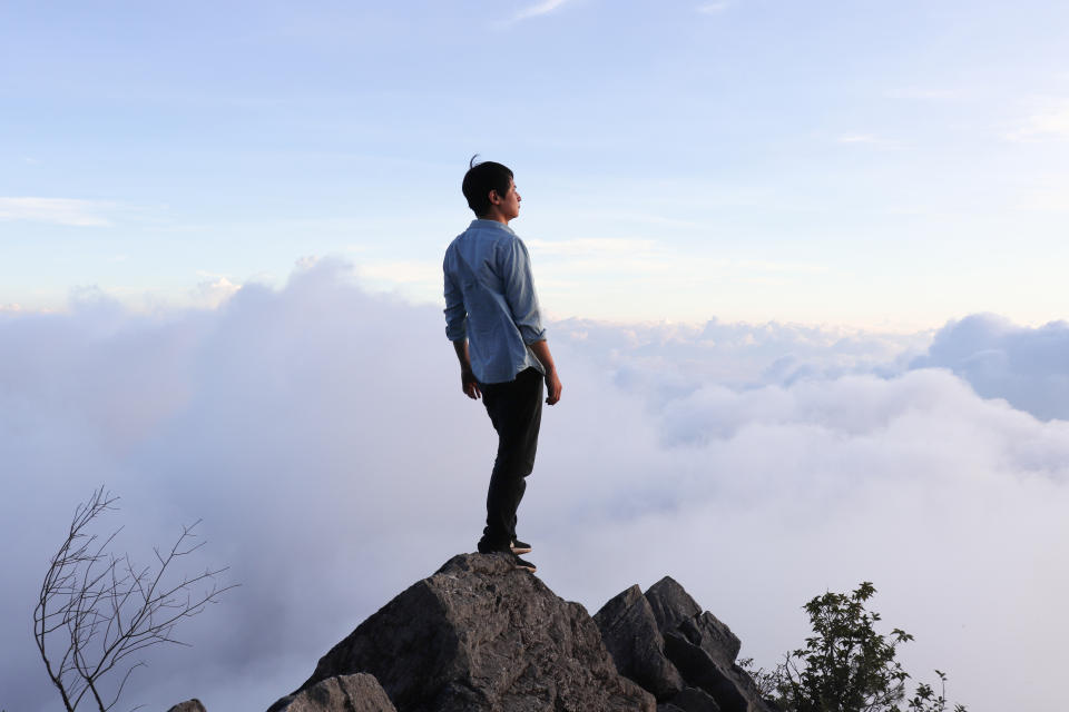 Homme asiatique debout au sommet de la colline.
