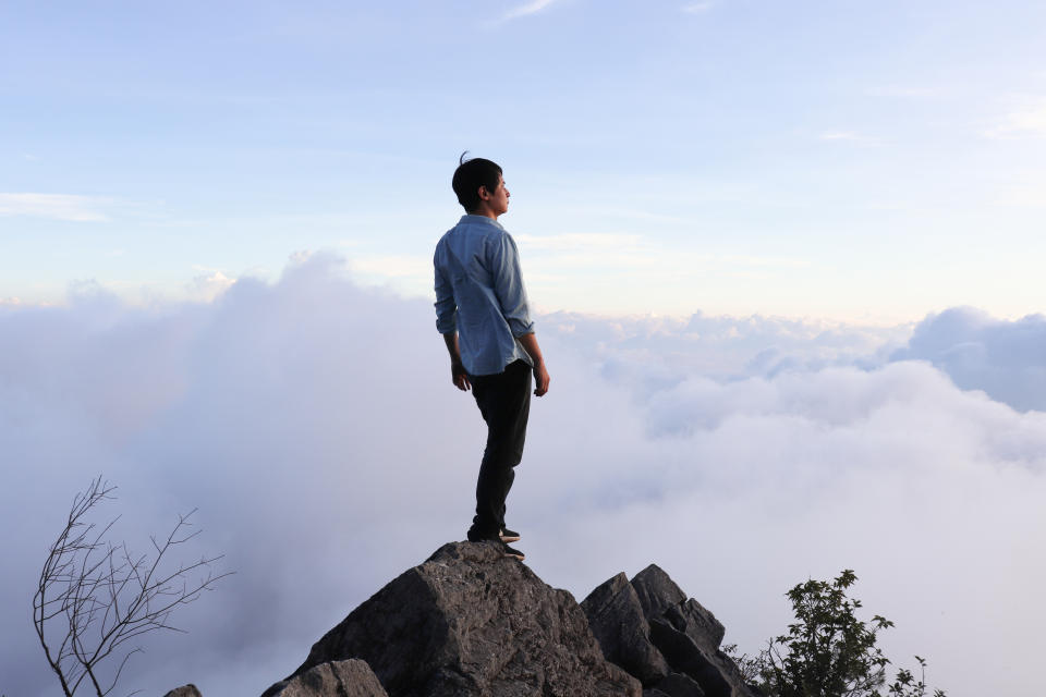 Asian man standing on the hilltop.