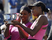 FILE - Serena Williams, left, of the United States, and her sister Venus examine the championship trophy after winning the women's doubles championship over Cara Black, of Zimbabwe, and Liezel Huber, of the United States, at the U.S. Open tennis tournament in New York, Monday, Sept. 14, 2009. Serena and Venus Williams were given a wild-card entry for women's doubles at the U.S. Open on Saturday, Aug. 27, 2022, making it their first tournament as a team in more than four years. (AP Photo/Darron Cummings, File)
