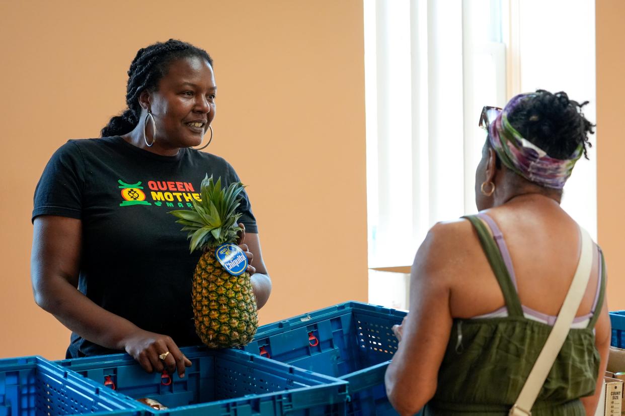 Mona Jenkins, of Queen Mother's Market Cooperative, passes out food at the the Alexandra apartment building in Walnut Hills in August.