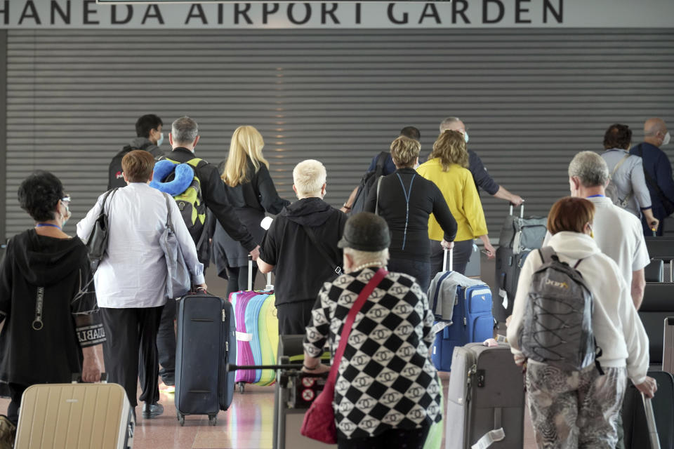 Foreign travellers walk upon arrival at the Haneda International Airport Tuesday, Oct. 11, 2022, in Tokyo. Japan's strict border restrictions are eased, allowing tourists to easily enter for the first time since the start of the COVID-19 pandemic. Independent tourists are again welcomed, not just those traveling with authorized groups. (AP Photo/Eugene Hoshiko)