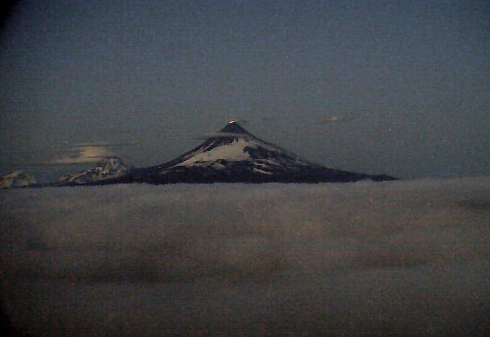 This web camera image provided by the U.S. Geological Survey shows glowing lava erupting within the summit crater of Shishaldin around 12:30 a.m. AKDT, Tuesday, July 18, 2023, as seen from the WTUG webcam located NW of the volcano. The ongoing eruption of a remote the volcano in Alaska's Aleutian Islands produced an ash cloud so large Tuesday warnings were sent to pilots about potentially dangerous conditions.(Alaska Volcano Observatory/U.S. Geological Survey via AP)