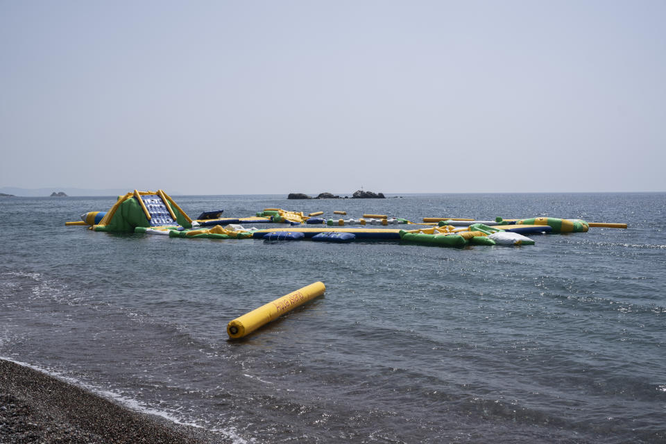 FILE - An abandoned floating water park is seen from the beach after a wildfire, near Gennadi village, on the Aegean Sea island of Rhodes, southeastern Greece, on July 27, 2023. Tourists at a seaside hotel on the Greek island of Rhodes snatched up pails of pool water and damp towels as flames approached, rushing to help staffers and locals extinguish one of the wildfires threatening Mediterranean locales during recent heat waves. (AP Photo/Petros Giannakouris, File)