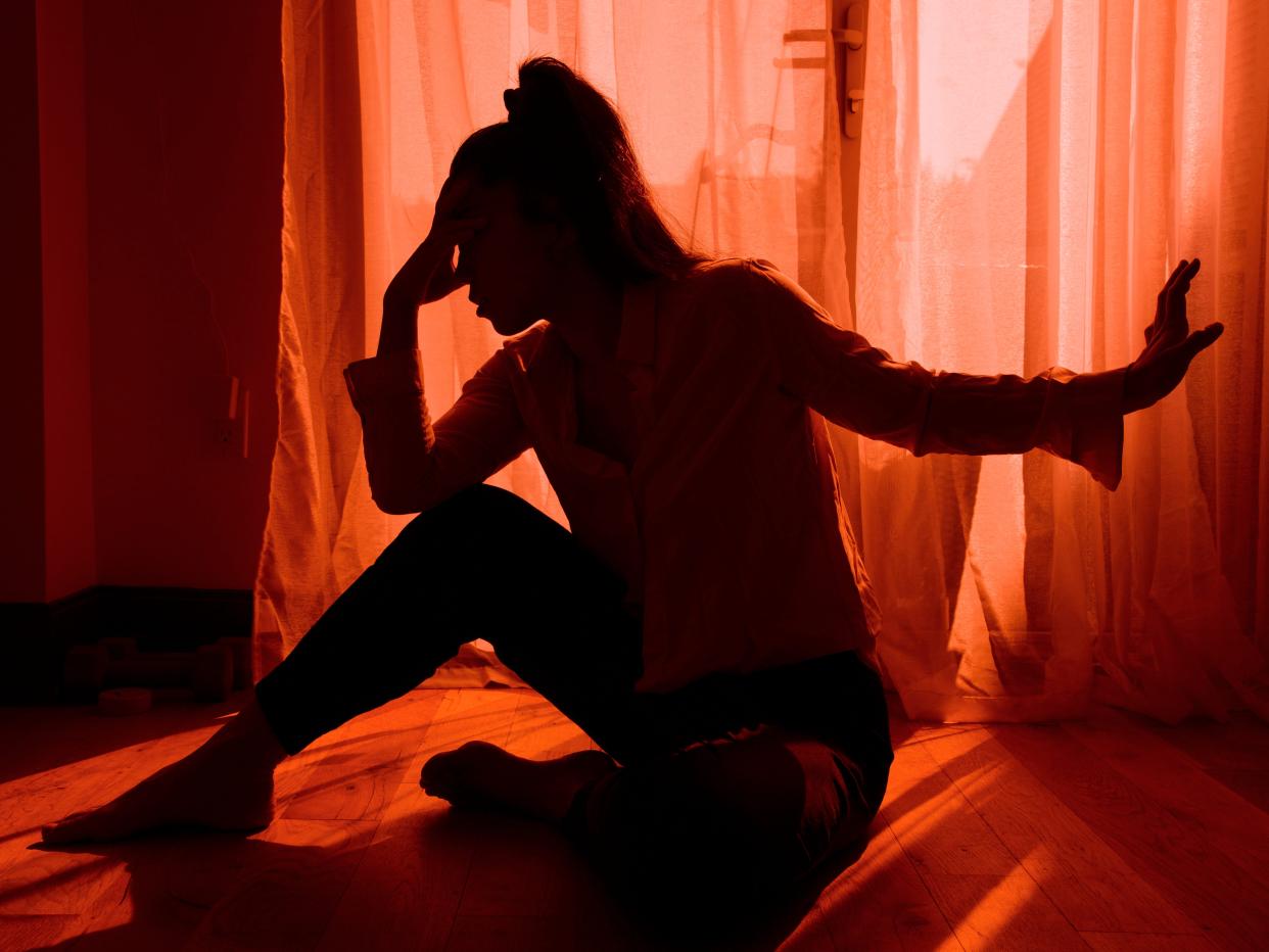 Woman looking stressed and upset against a window.