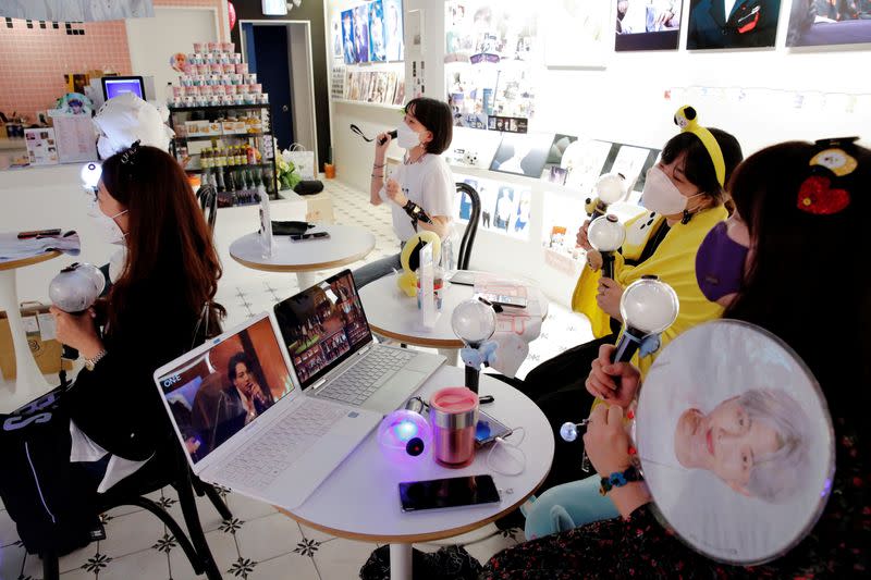 Fans of K-pop idol boy band BTS enjoy as they watch a live streaming online concert, wearing a protective masks at a cafe, in Seoul