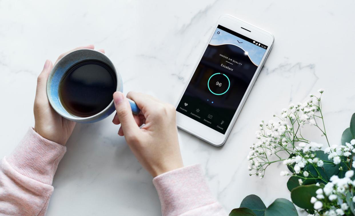 Woman checks the air quality in her home using the DARWIN System's accompanying mobile app.