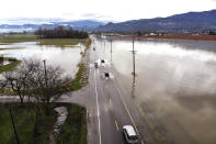 In this photo taken from a drone, traffic navigates a flooded highway headed into Sumas, Wash., Monday, Nov. 29, 2021. Weather officials are urging Northwest residents to remain alert because more rain is on the way to an area with lingering water from extreme weather from a previous storm. (AP Photo/Elaine Thompson)