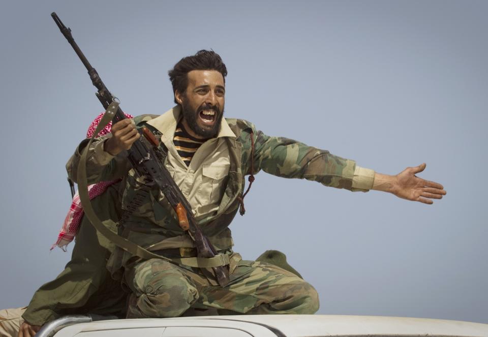 FILE - In this March 29, 2011, file photo, a Libyan rebel urges people to leave as shelling from Gadhafi's forces started landing on the frontline outside of Bin Jawaad, 150 kilometers (93 miles) east of Sirte, central Libya. Ten years ago, an uprising in Tunisia opened the way for a wave of popular revolts against authoritarian rulers across the Middle East known as the Arab Spring. For a brief window as leaders fell, it seemed the move toward greater democracy was irreversible. Instead, the region saw its most destructive decade of the modern era. Syria, Yemen, Libya and Iraq have been torn apart by wars, displacement and humanitarian crisis. (AP Photo/Anja Niedringhaus, File)