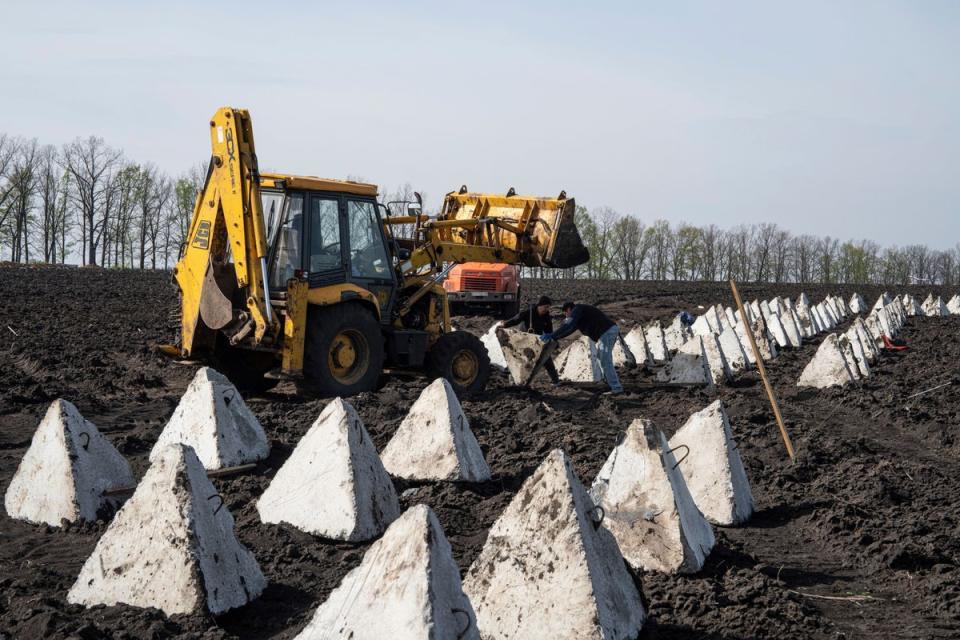 Украинские рабочие устанавливают противотанковые «зубы дракона» во время строительства новых оборонительных позиций в Харьковской области (АП)
