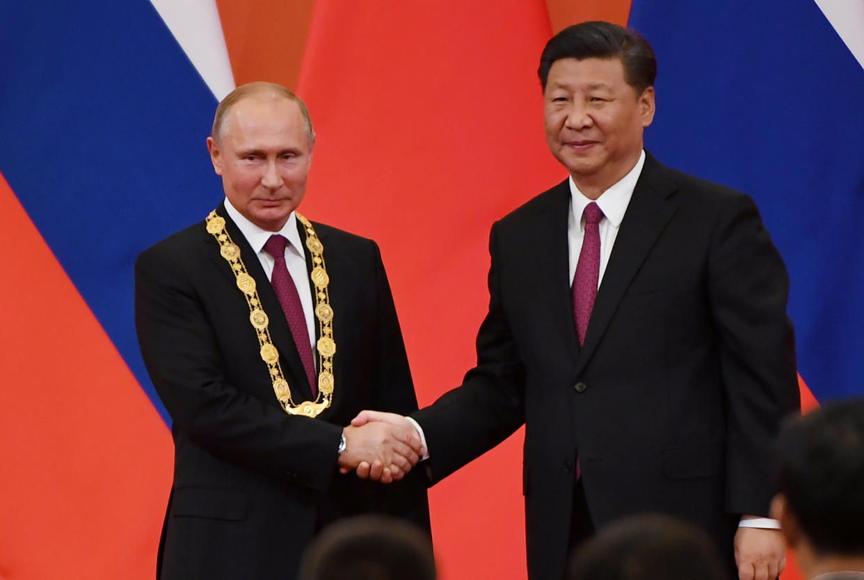 Chinese President Xi Jinping shakes the hand of Russian President Vladimir Putin after presenting him with the Friendship Medal.