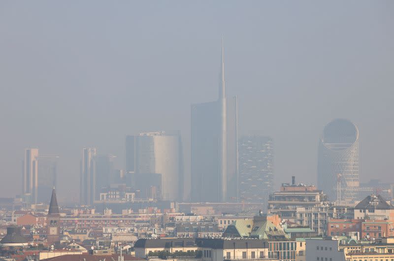 Vista general de edificios de gran altura, la torre UniCredit y el edificio Vertical Forest, cubiertos en smog en Milán, Italia