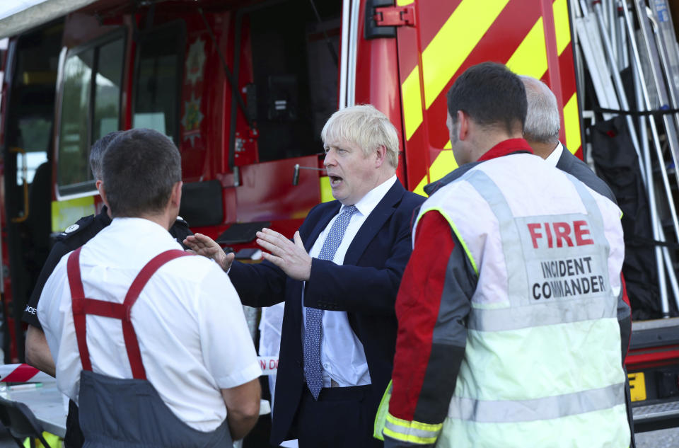 Britain's Prime Minister Boris Johnson meets with emergency crews during a visit to Whaley Bridge Football Club, after the Toddbrook Reservoir near the village of Whaley Bridge was damaged in heavy rainfall in Derbyshire, England, Friday, Aug. 2, 2019. A British military helicopter dropped sandbags Friday to shore up a reservoir wall as emergency services worked frantically to prevent a rain-damaged dam from collapsing. Engineers said they remain "very concerned" about the integrity of the 19th-century Toddbrook Reservoir, which contains around 1.3 million metric tons (1.5 million (U.S tons) of water. (Yui Mok/Pool photo via AP)