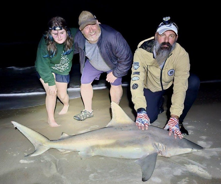 Dustin Smith (right) of NSB Shark Hunters helps release a catch for Madeline and Rich.
