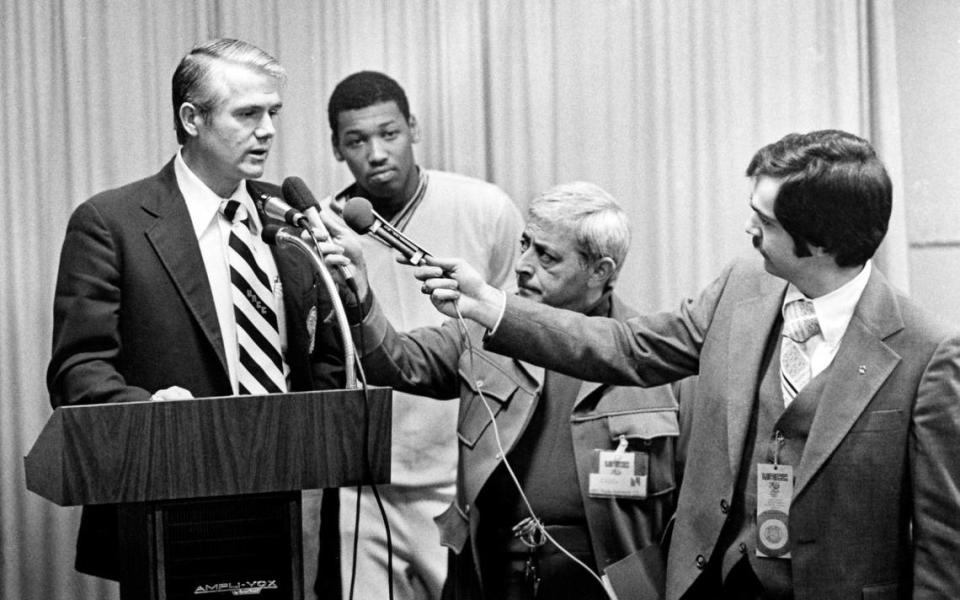 Former Charlotte 49ers basketball coach Lee Rose talks with reporters in 1977 as player Lew Massey looks on.