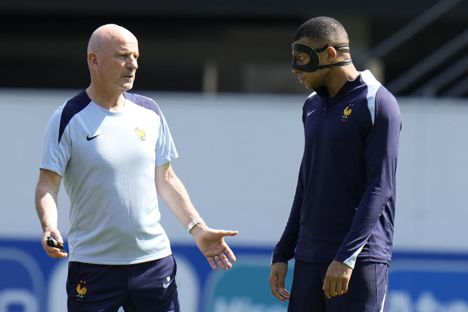 France's Kylian Mbappe speaks with a coach during a training session in Paderborn, Germany, Monday, June 24, 2024. France will play against Poland during their Group D soccer match at the Euro 2024 soccer tournament on June 25. (AP Photo/Hassan Ammar)