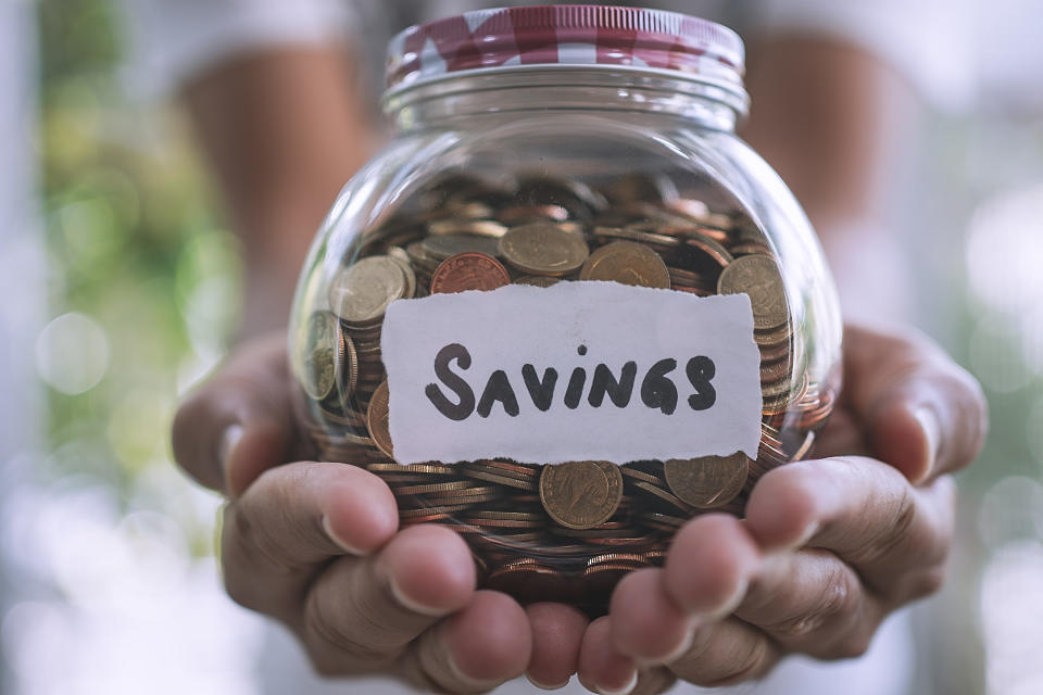 Person holding a jar of change labeled savings