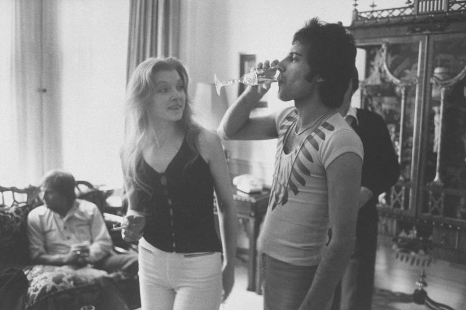 <p>Freddie Mercury drinking a glass of champagne as Mary Austin looks on during party for friends in 1977.</p>
