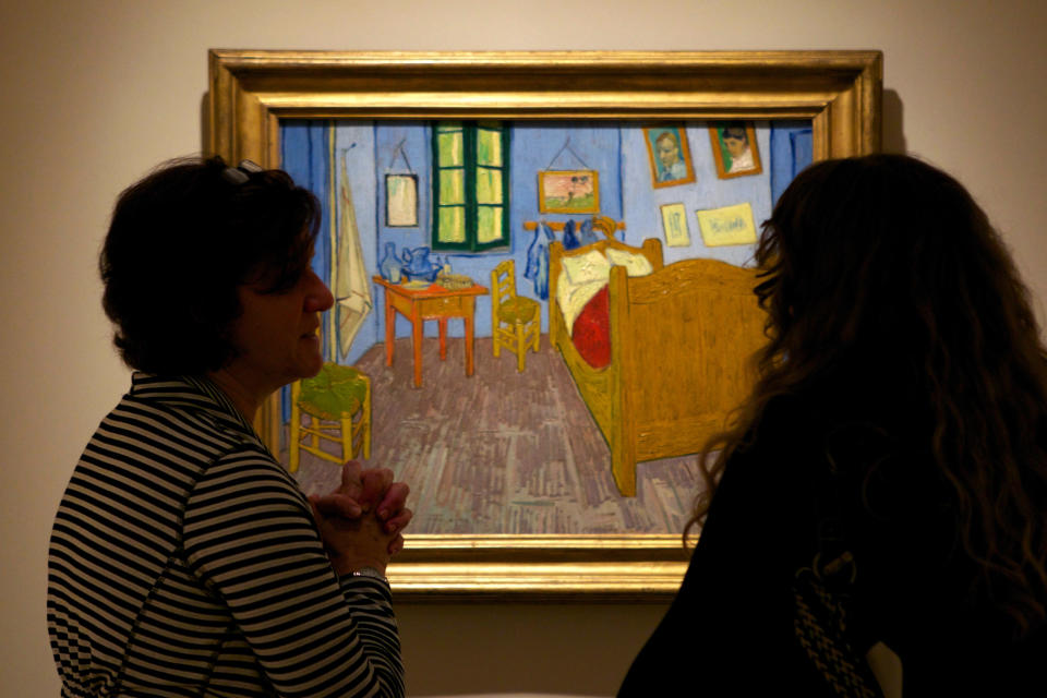 In this Oct. 8, 2013 photo, women discuss Vincent van Gogh's "The Bedroom at Arles," on display at The Phillips Collection in Washington. In the midst of the shutdown of federally funded museums, the private Phillips Collection is launching the first major exhibition of Vincent van Gogh’s artwork in Washington in 15 years. (AP Photo/Molly Riley)