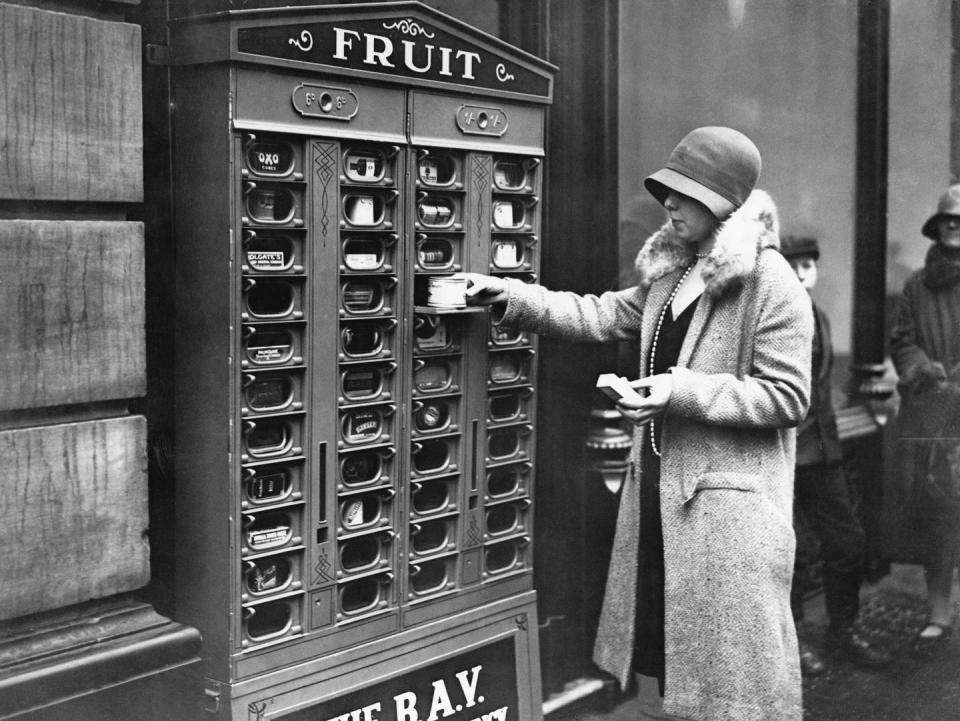 <p>A photographer captures a shopper in London, England, as she fetches a snack from a street-side vending machine.</p>