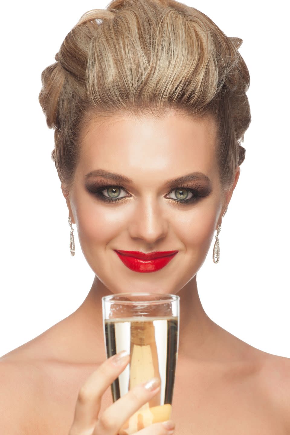 smiling woman with bright red lipstick and hair swept back high off her forehead and into a braid with a glass of champagne