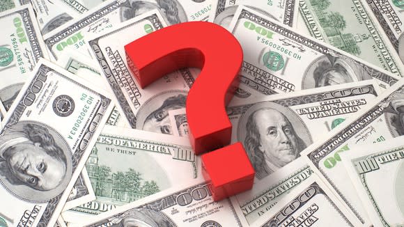 Red question mark on top of scattered pile of $100 bills