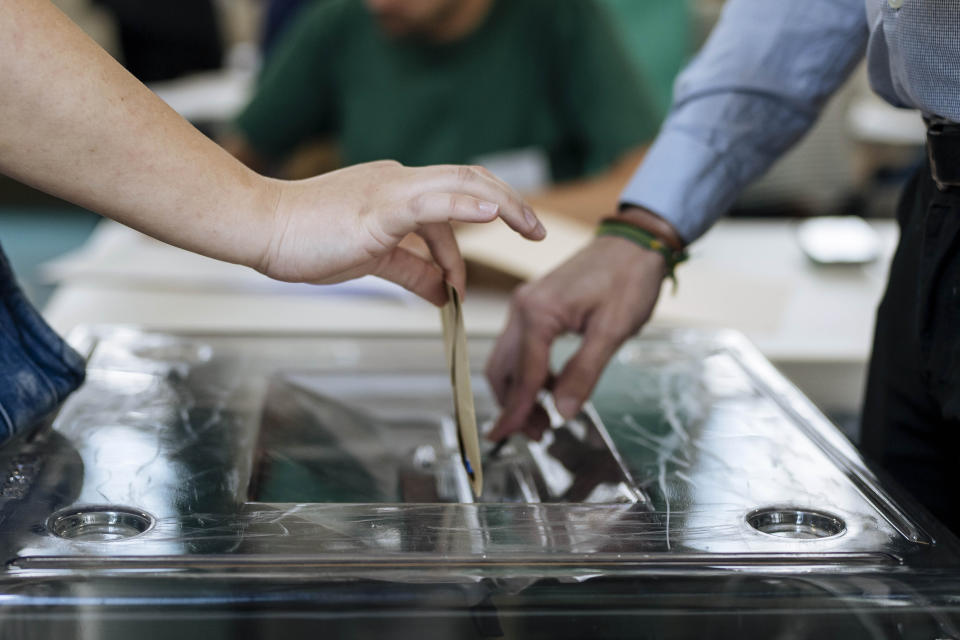 A woman, left, casts her ballot for the European Parliament election, Sunday, June 9, 2024 in Paris. Polling stations opened across Europe on Sunday as voters from 20 countries cast ballots in elections that are expected to shift the European Union's parliament to the right and could reshape the future direction of the world's biggest trading bloc. (AP Photo/Lewis Joly)