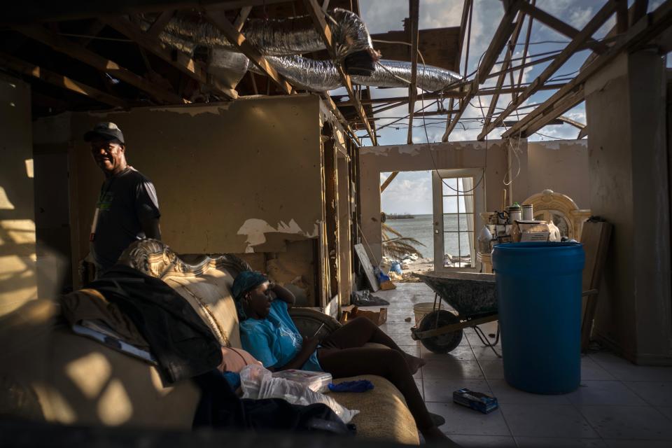 Phil Thomas, left, walks next to his daughter Ebony Thomas as she looks at her phone inside their home, shattered by Hurricane Dorian in Mclean's Town, Grand Bahama, Bahamas, Wednesday Sept. 11, 2019. Phil lost three members of his family in the Hurricane. (AP Photo / Ramon Espinosa)