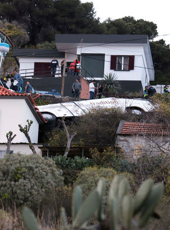 People stand next to the wreckage of a bus after an accident in Canico, in the Portuguese Island of Madeira, April 17, 2019. REUTERS/Duarte Sa