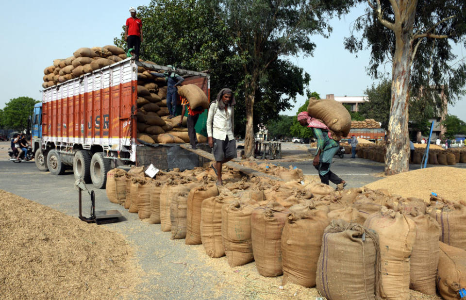 Workers load wheat from a trailer at a wholesale grain market on May 19, 2022 in New Delhi, India.<span class="copyright">Sonu Mehta/Hindustan Times via Getty Images</span>