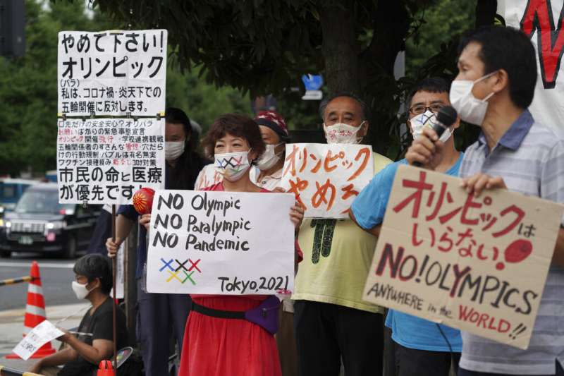 反對舉行東京奧運跟帕運的日本民眾，在總理大臣官邸附近舉牌抗議。（美聯社）