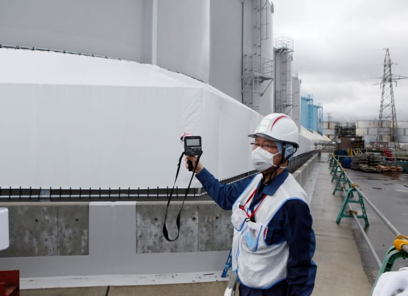 An employee of Tokyo Electric Power Co's uses a geiger counter next to storage tanks for radioactive water at tsunami-crippled Fukushima Daiichi nuclear power plant in Okuma town, Fukushima prefecture