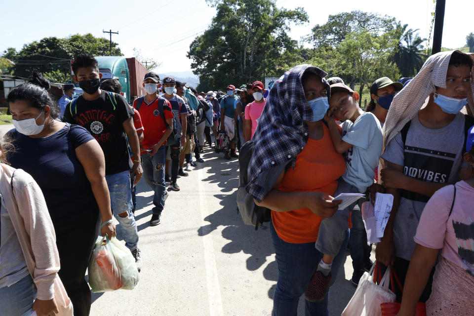 Migrants who are part of a caravan hoping to reach the United States, wait in a line as they wait to have their documents checked by police in Corinto, Honduras, Saturday, Jan. 15, 2022. (AP Photo/Delmer Martinez)