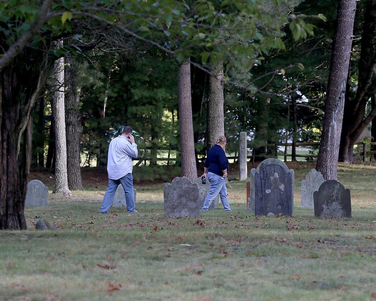 A man and a woman look at headstones and learn about the people buried at the Myles Standish Burial Ground in Duxbury, the oldest maintained cemetery in the U.S.