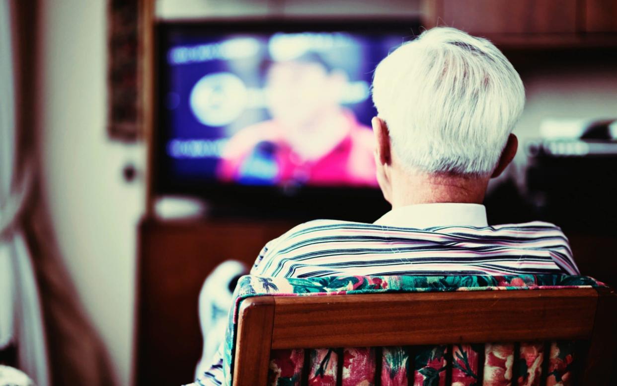 A 90-year-old old man is seen backview, seated in front of a television, alone. He may be a resident of a care home. - Getty Images/Getty Images