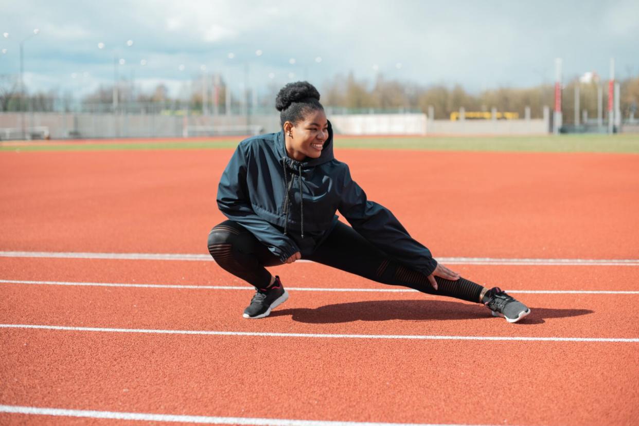 black girl on track doing side stretch before run