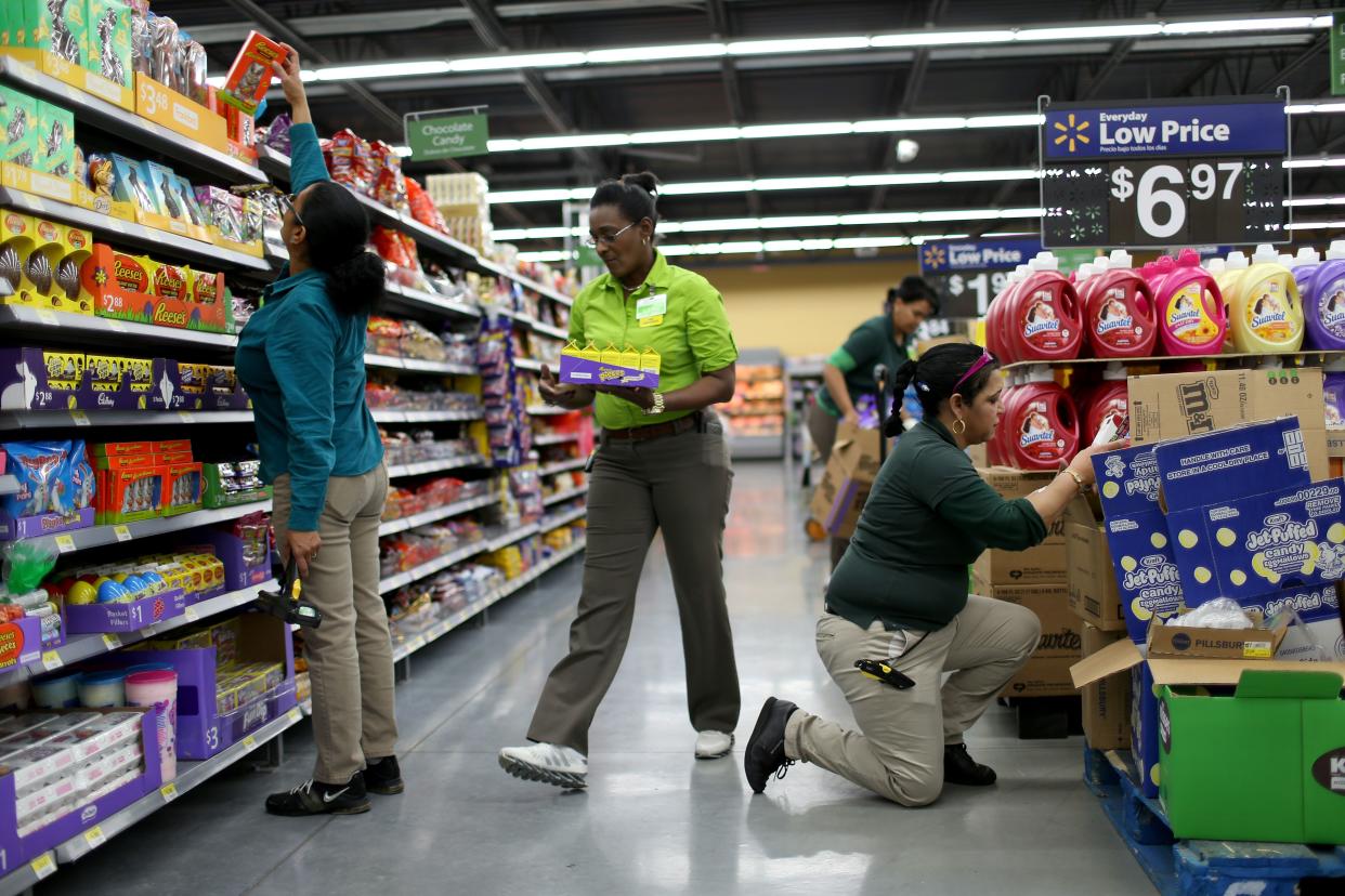 Walmart employees Iliana Sanchez (C) and her fellow employees stock the shelves at a Walmart store