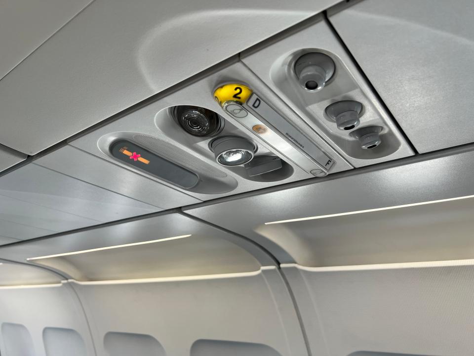 The air conditioning units and lights and a no-smoking sign overhead on a Beond A319